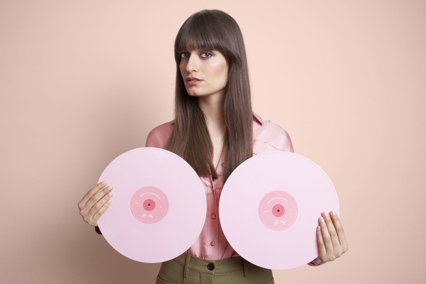 Clara Luciani posant deux vinyls rose devant sa poitrine pour la campagne de sensibilisation #MixYourBoobs pour Octobre rose
